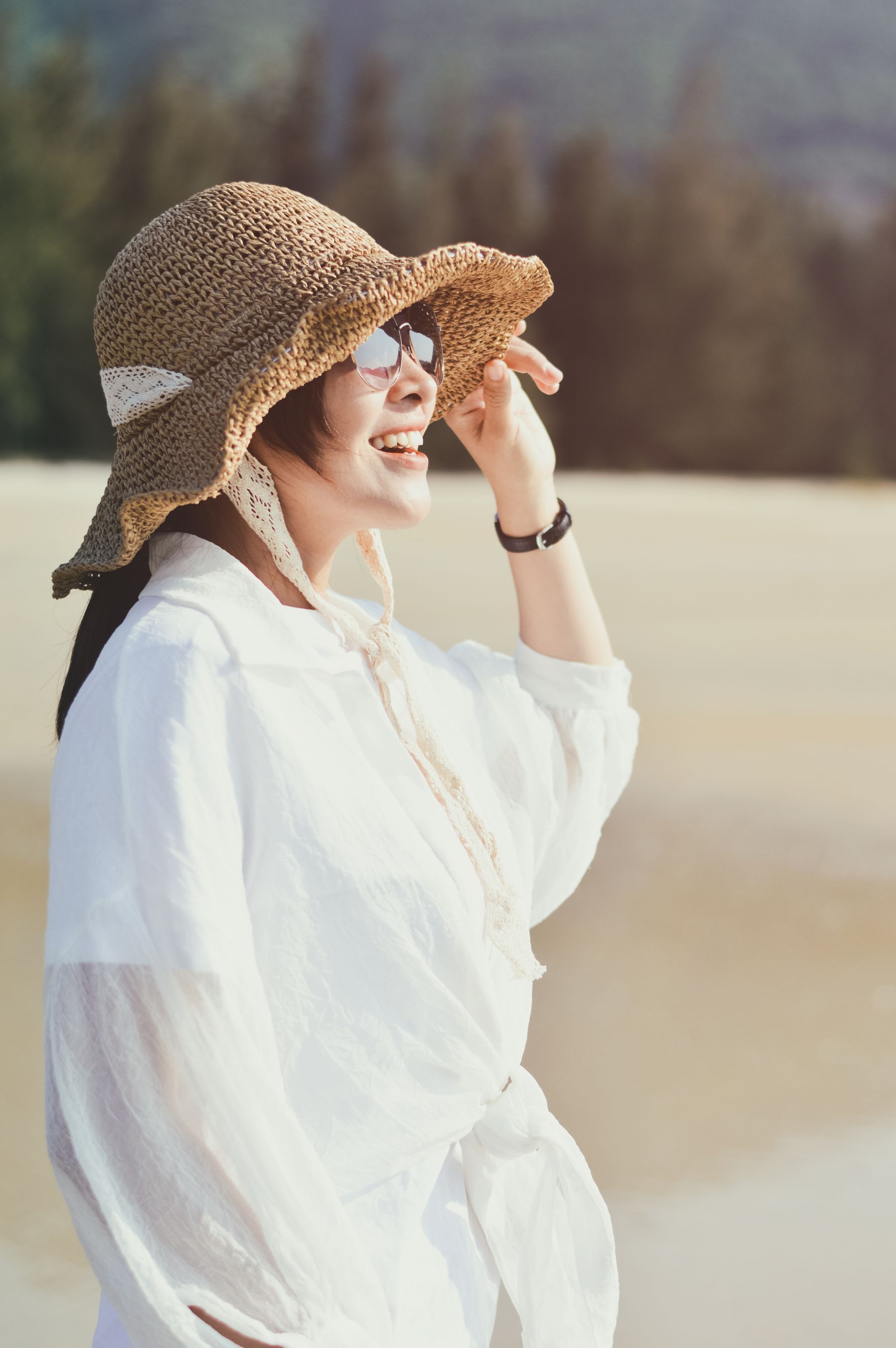 Femme portant un chapeau à larges bords, des lunettes de soleil et une chemise claire